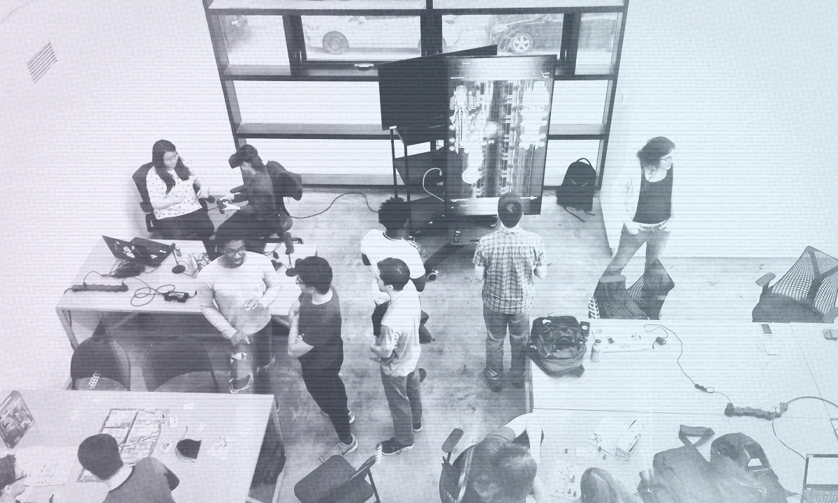 Game developers gathered at a community event, playing games and collaborating around shared workspaces